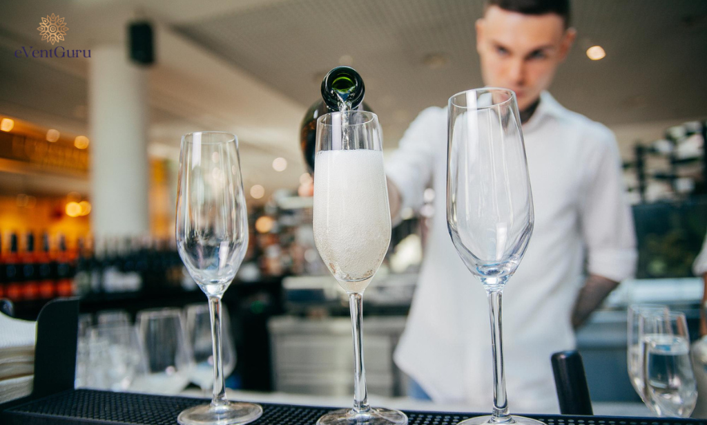 There is a bartender who pours champagne into a glass