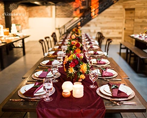 Long table with luxury plates and decorated with colorful flowers and candles