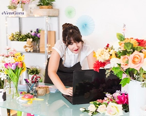 Female florist working on laptop with flowers on desk